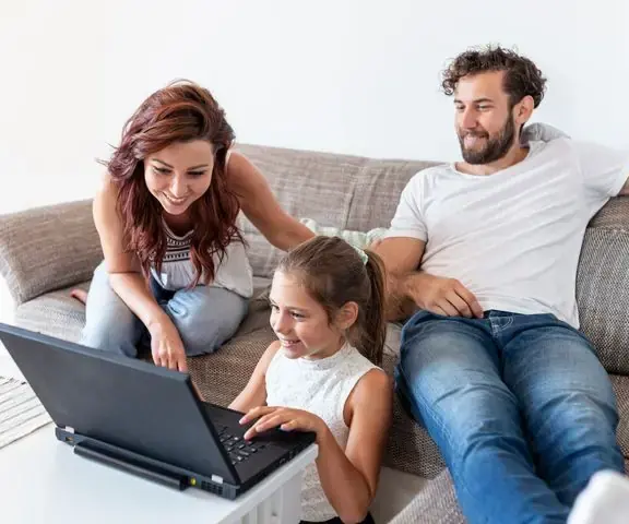 Familia en el sofá comparando alojamientos en una notebook